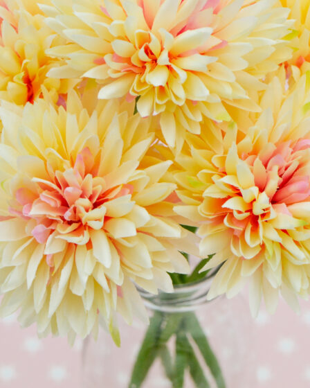 bunch-of-yellow-and-pink-flowers-in-glass-jar-on-top-of-a-pink-starry-background